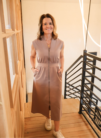 Model wearing a sleeveless mocha zip front dress with a sleek mid-length design, showcasing a timeless and versatile neutral-toned look.